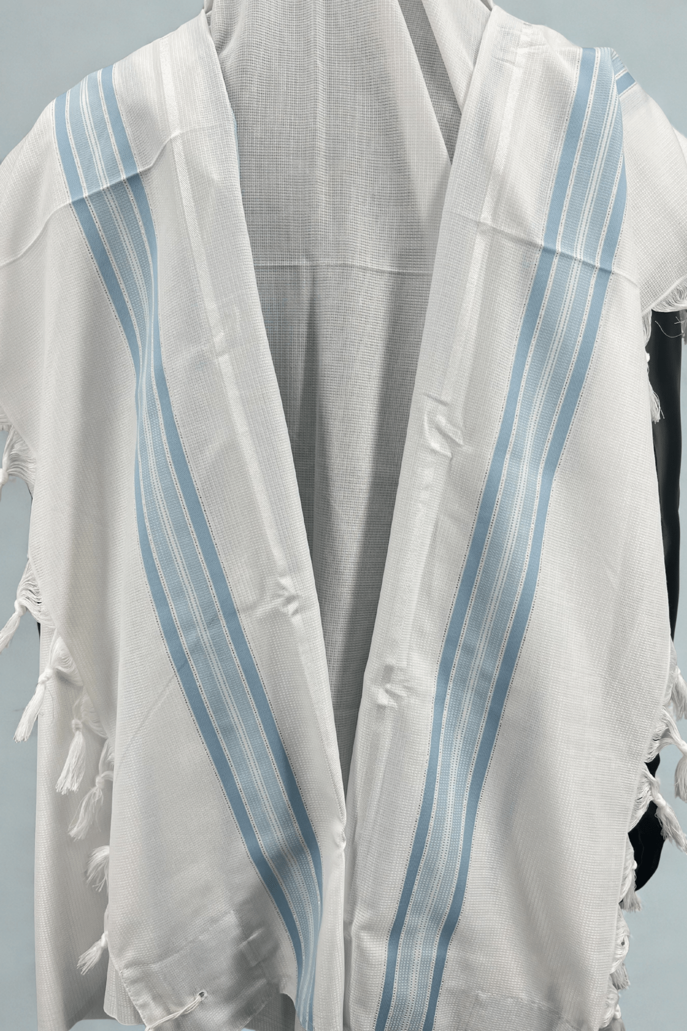 White Tallit Chatanim with blue stripes and tassels on a light gray background