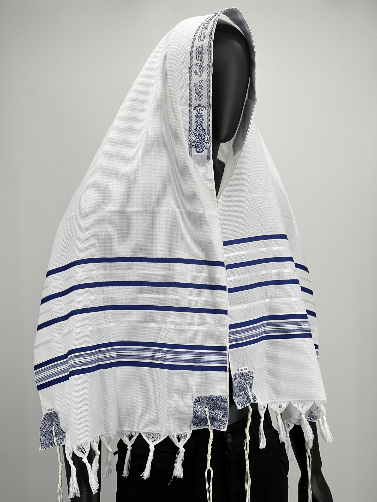 tallit prayer shawl with blue stripes and decorative corners, worn draped over the head and shoulders of a mannequin.