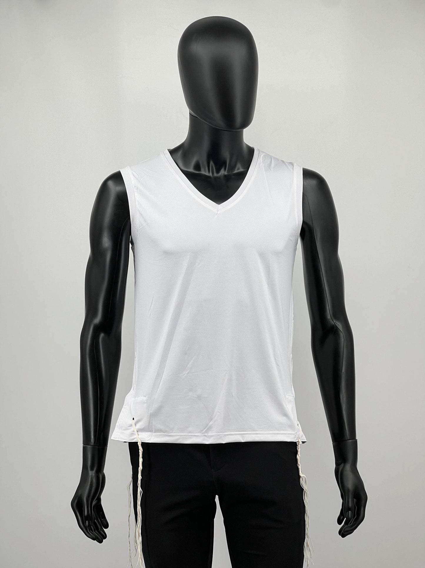 Mannequin wearing a white sleeveless tzitzit tank top and black pants on a gray background