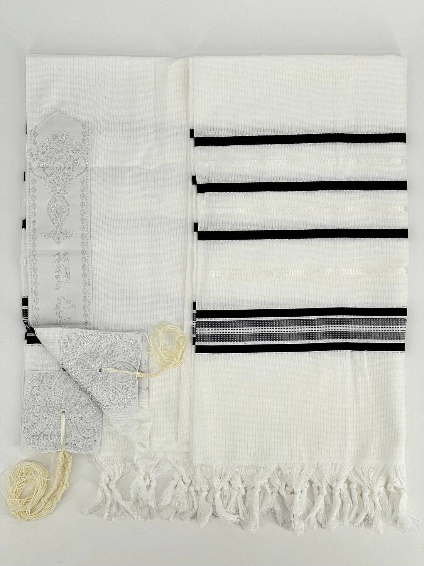 Flat-lay image of a white Acrylic Tallit Chatanim with black stripes and silver decorative elements.