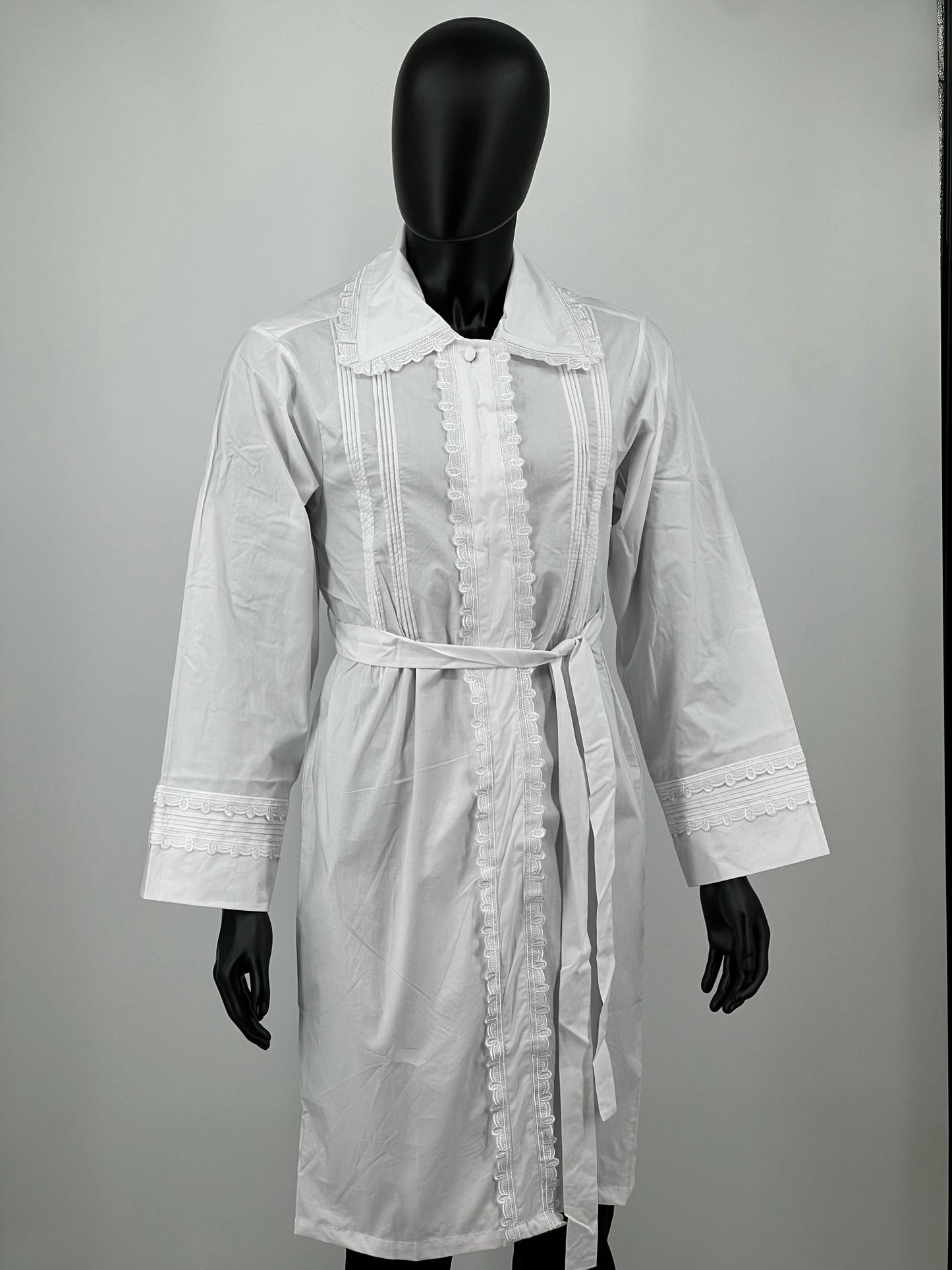 White kittel with lace details on a mannequin against a plain background.