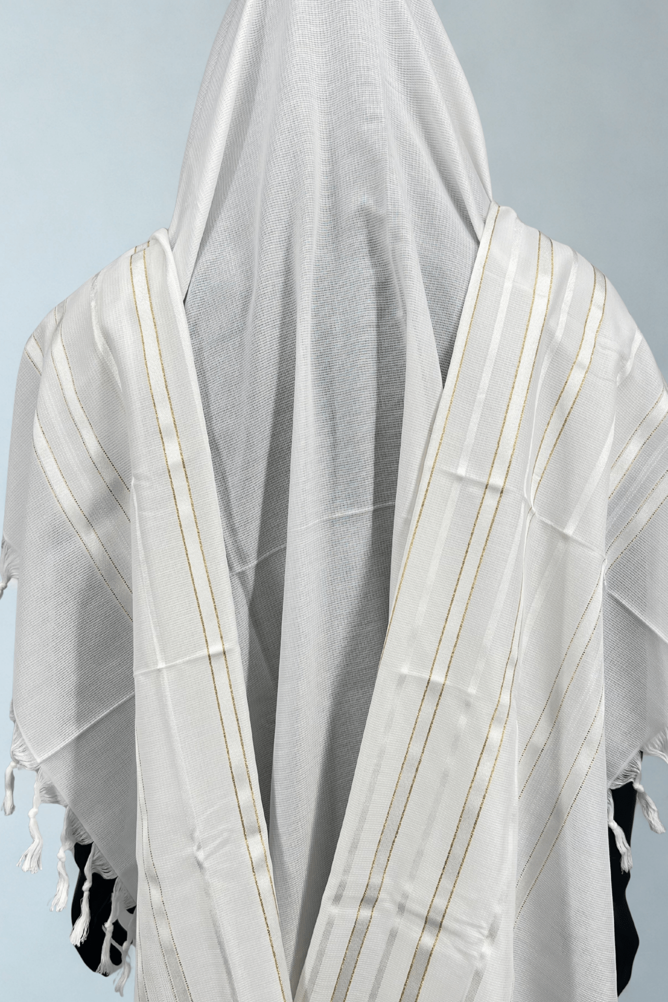 White prayer shawl with fringe details on a light blue background