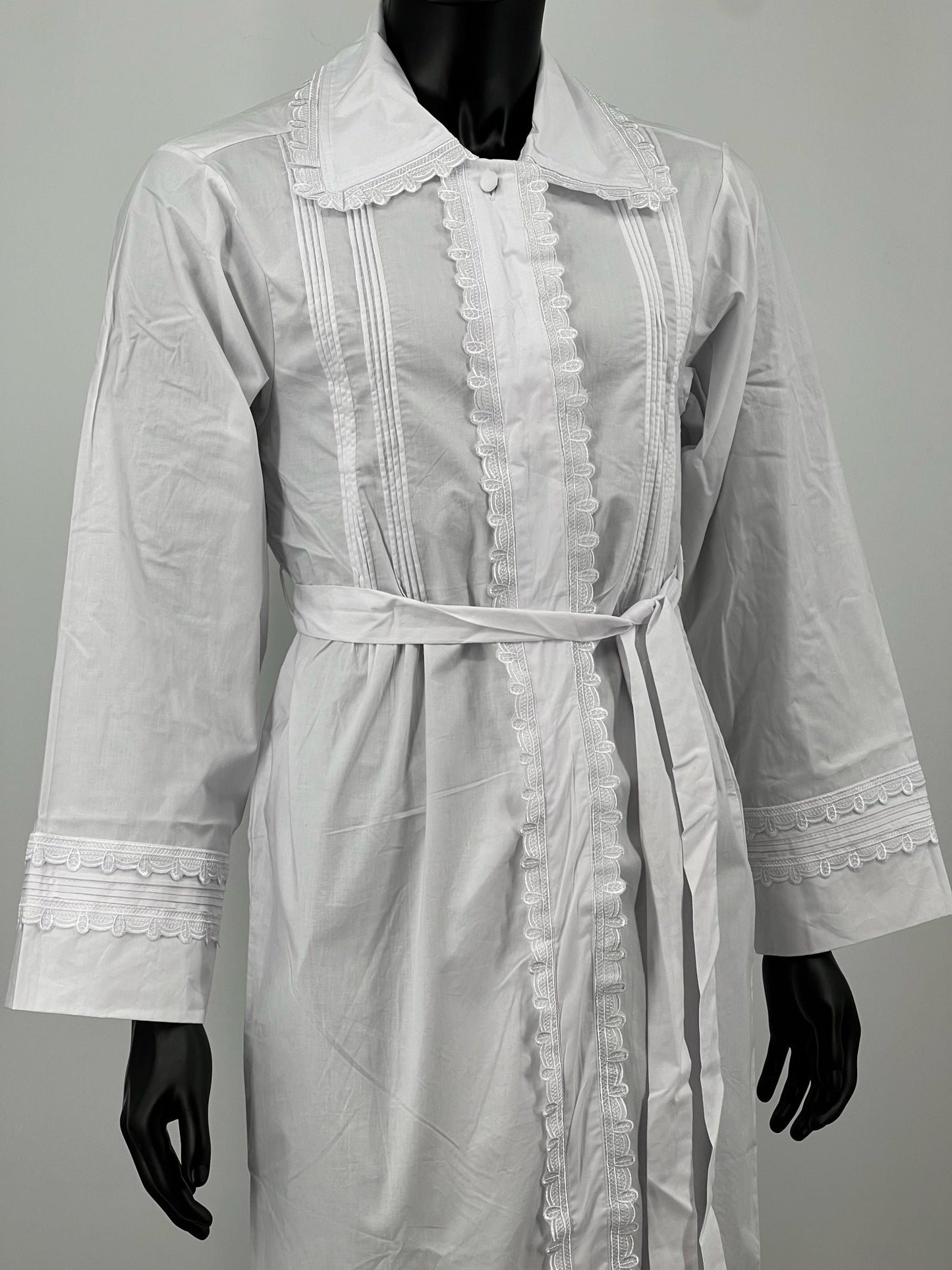 White Kittel with lace details on a mannequin against a plain background.