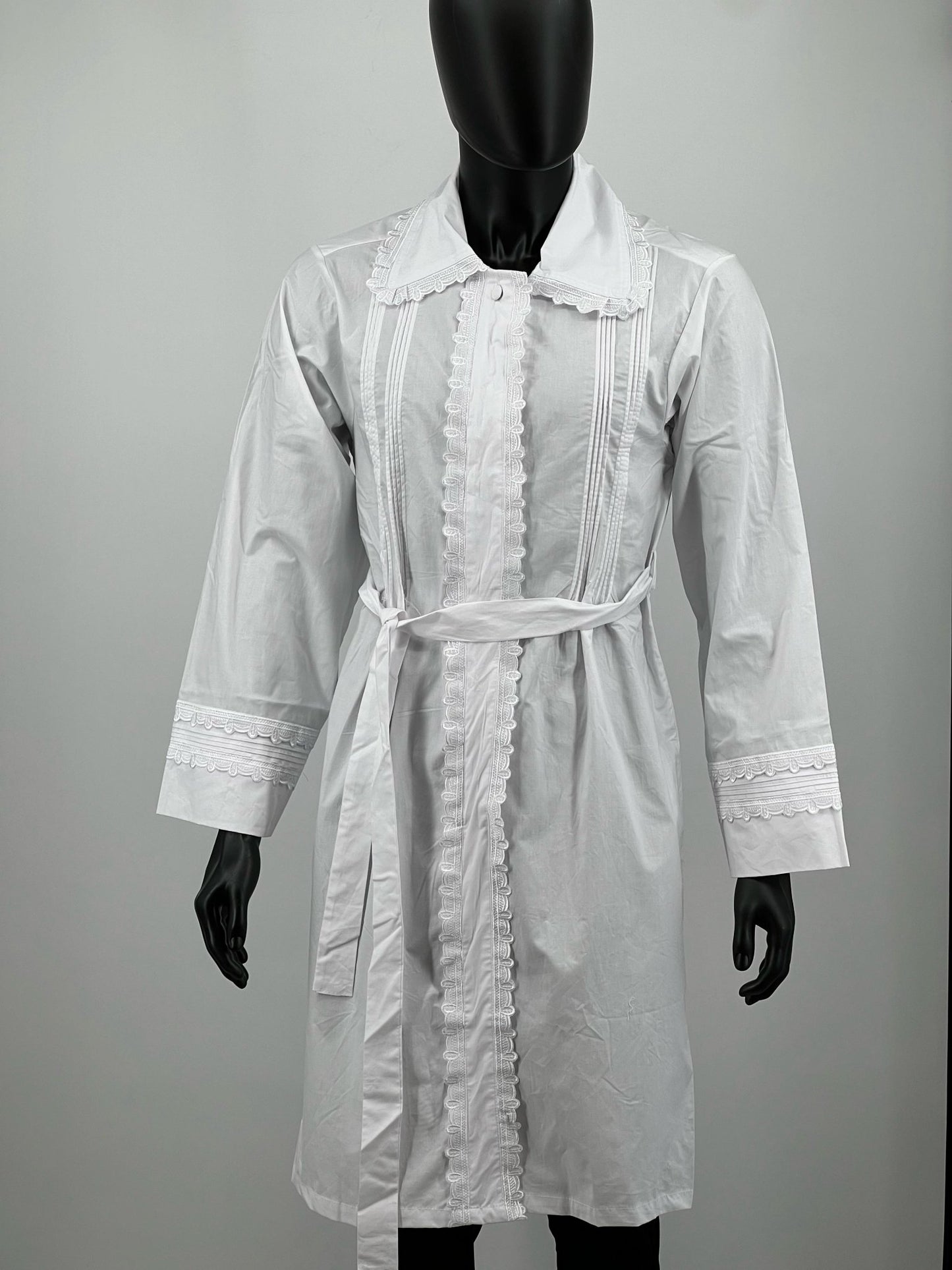 White Kittel with lace details on a mannequin against a plain background.