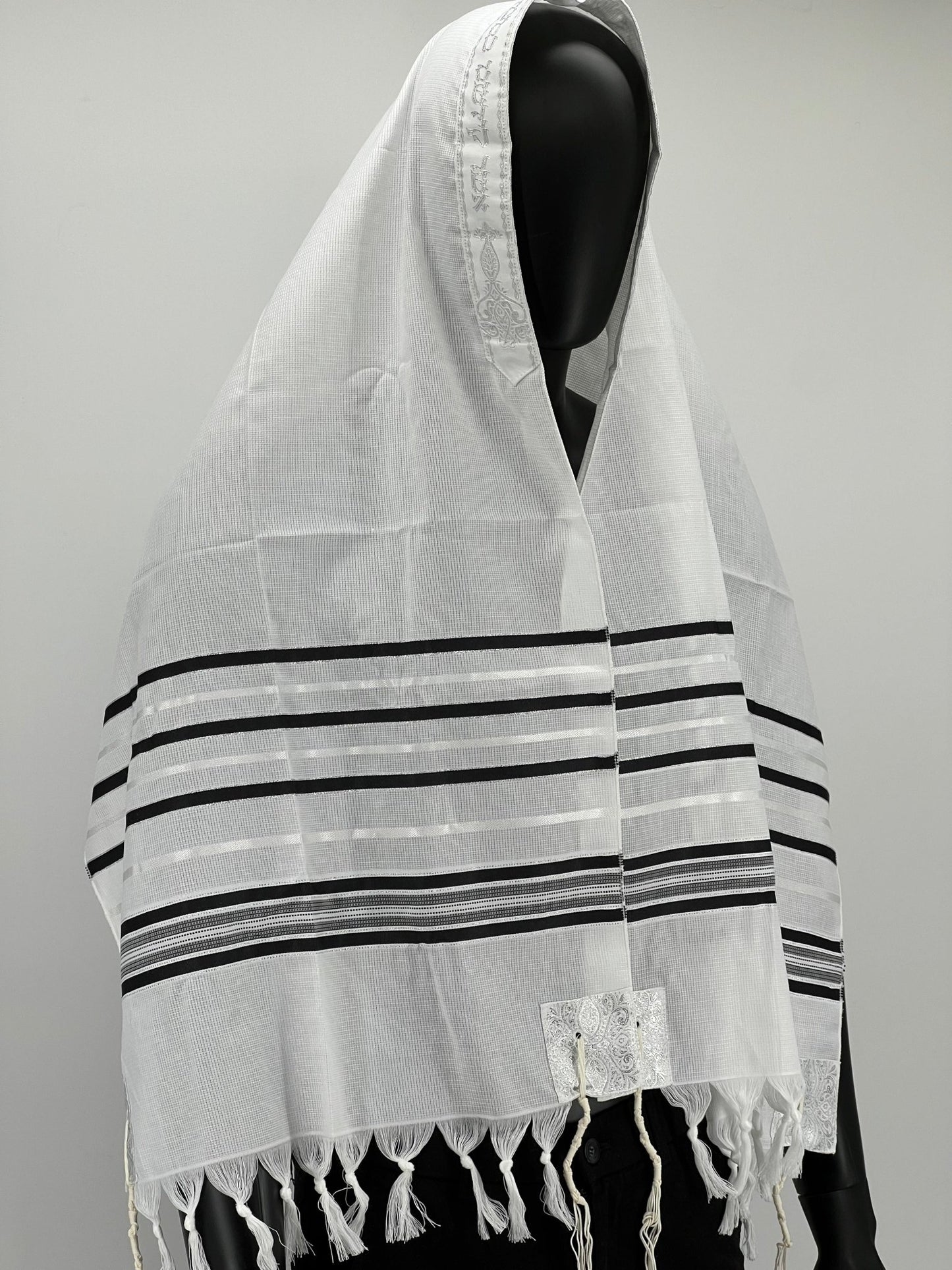 Mannequin wearing an acrylic Tallit scarf with black stripes and tzitzit fringes, draped over the head and shoulders.