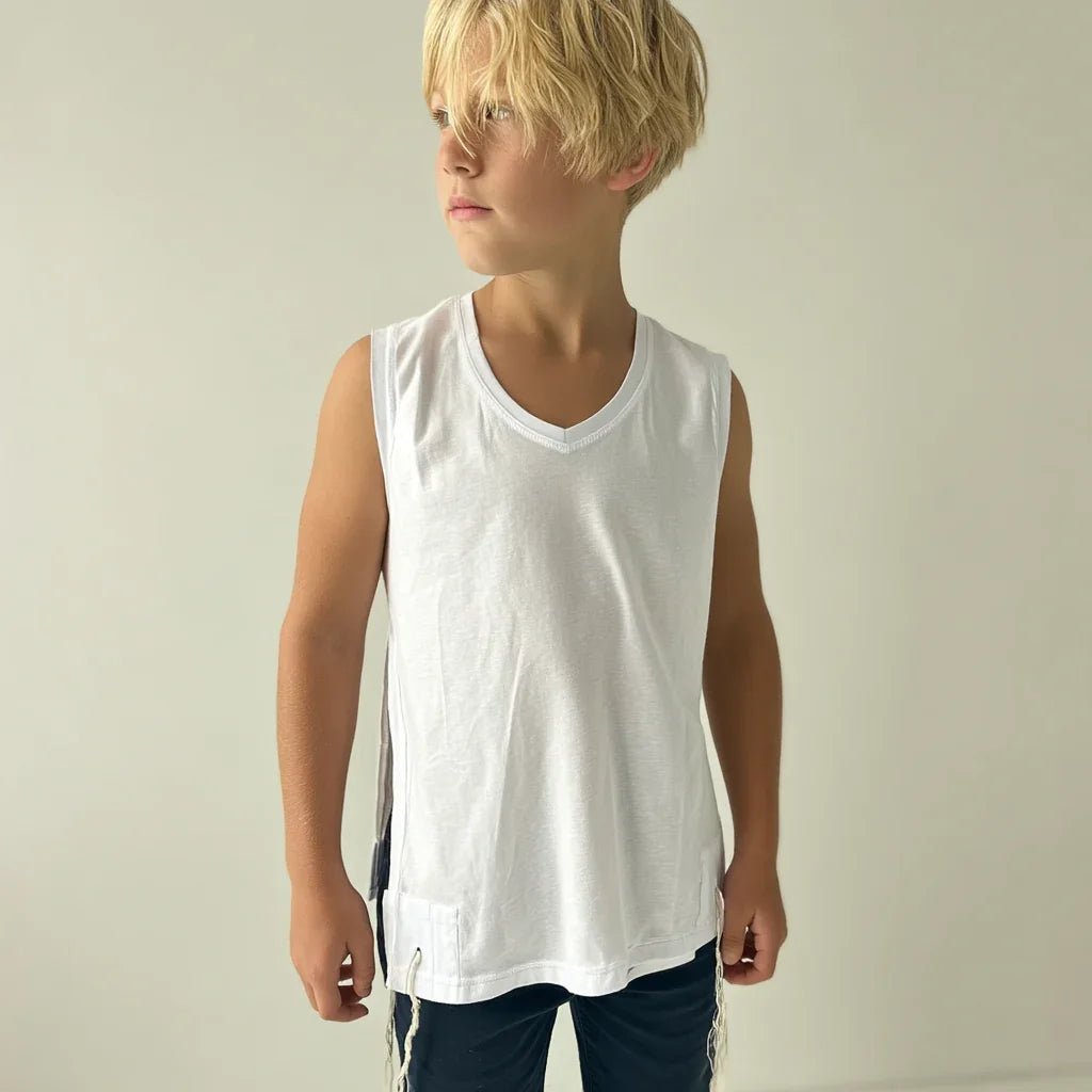 Young boy wearing a white Tzitzit T-shirt sleeveless against a plain background