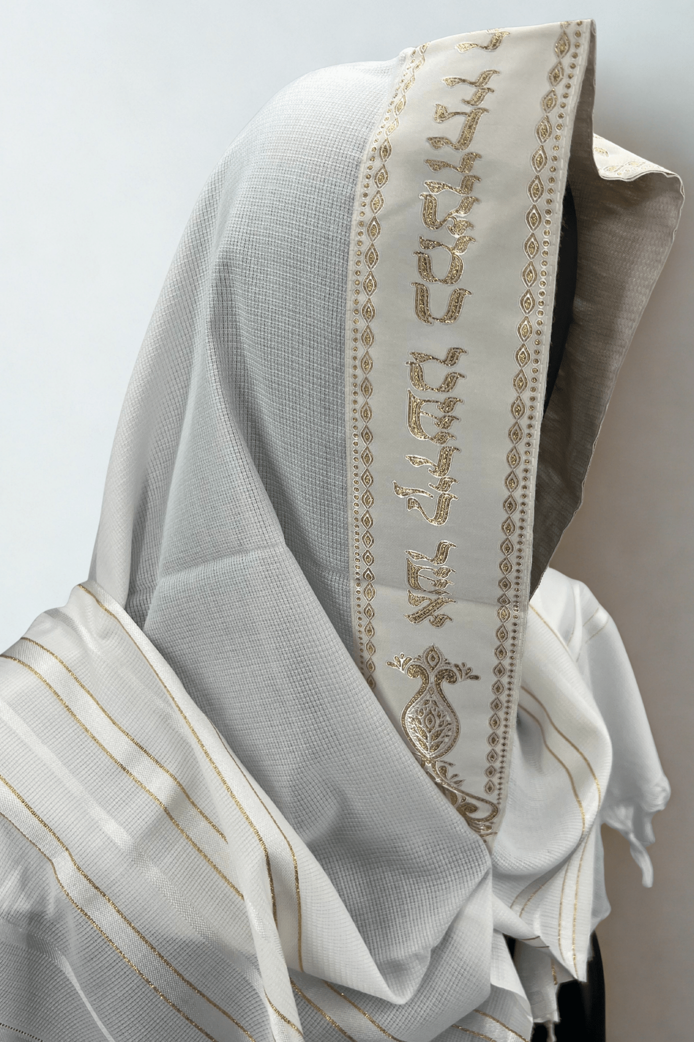 Close-up side view of a white Acrylic Tallit Chatanim with gold stripes and an embroidered atara (neckband)