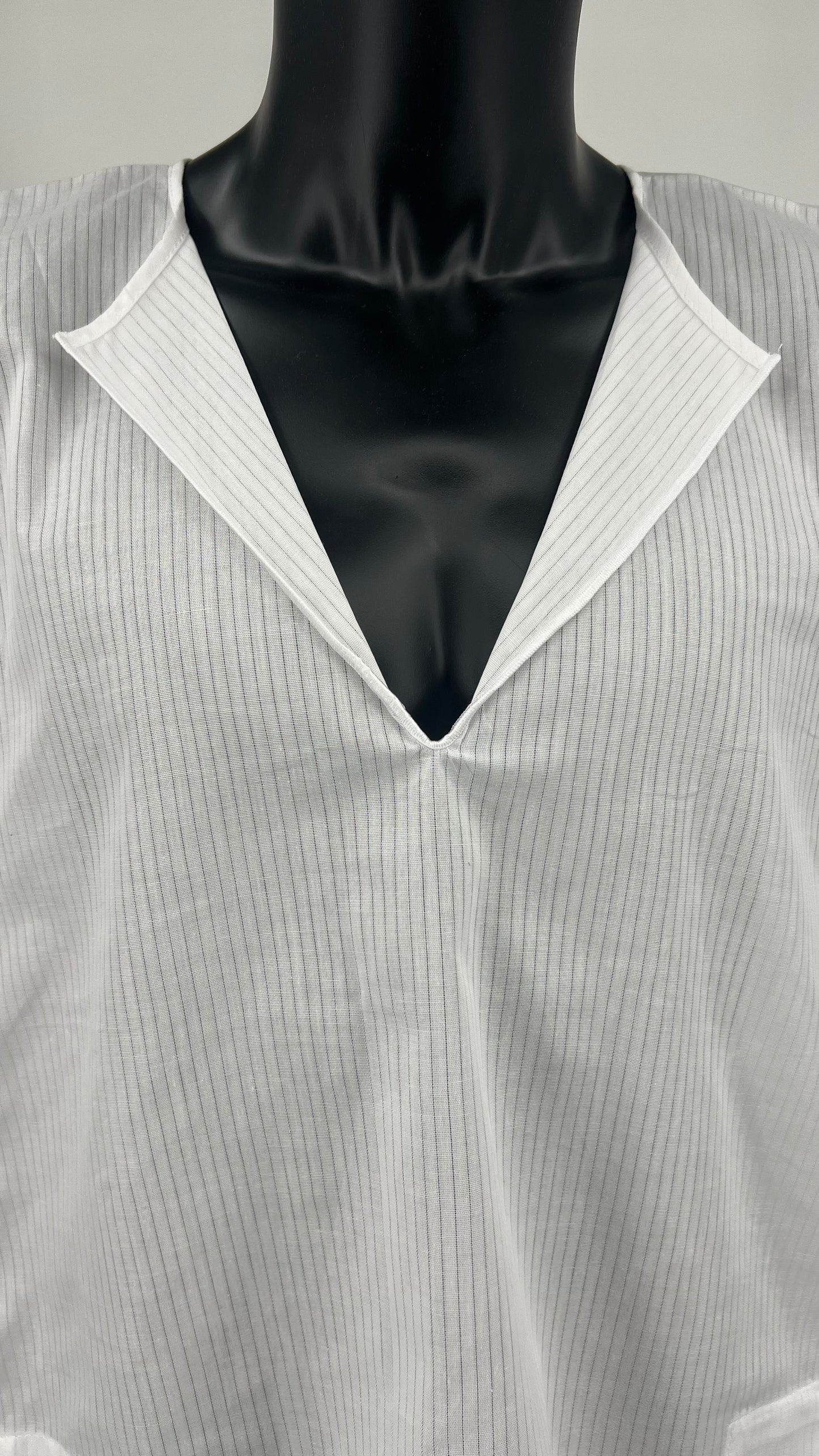 Close-up front view of a white cotton Tallit Katan worn on a black mannequin torso.