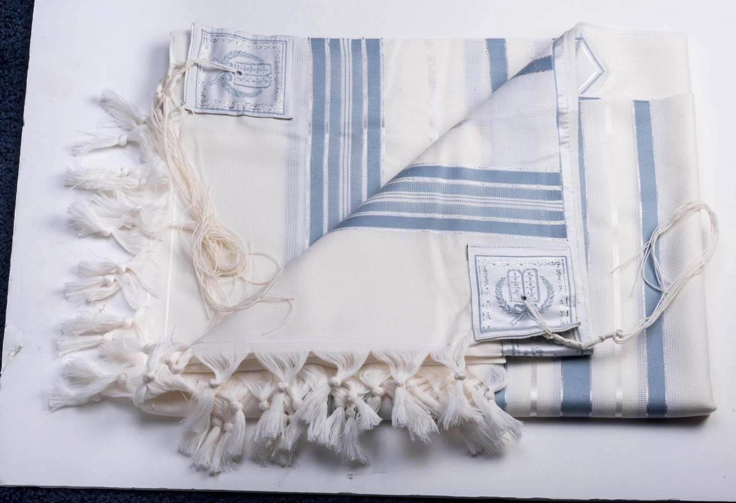 White tallit gadol with blue stripes on a white background