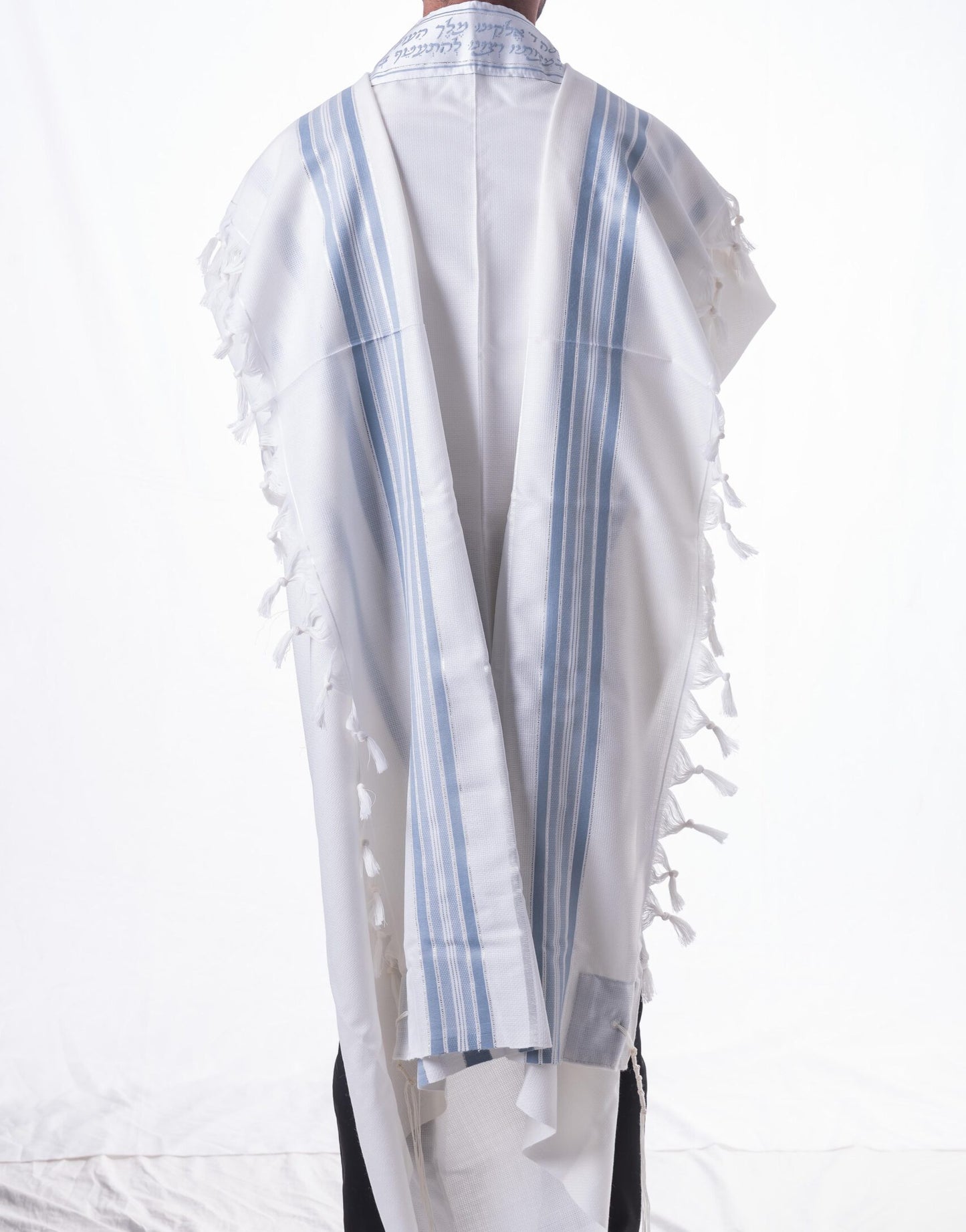 White wool tallit katan with blue stripes and fringes on a white background