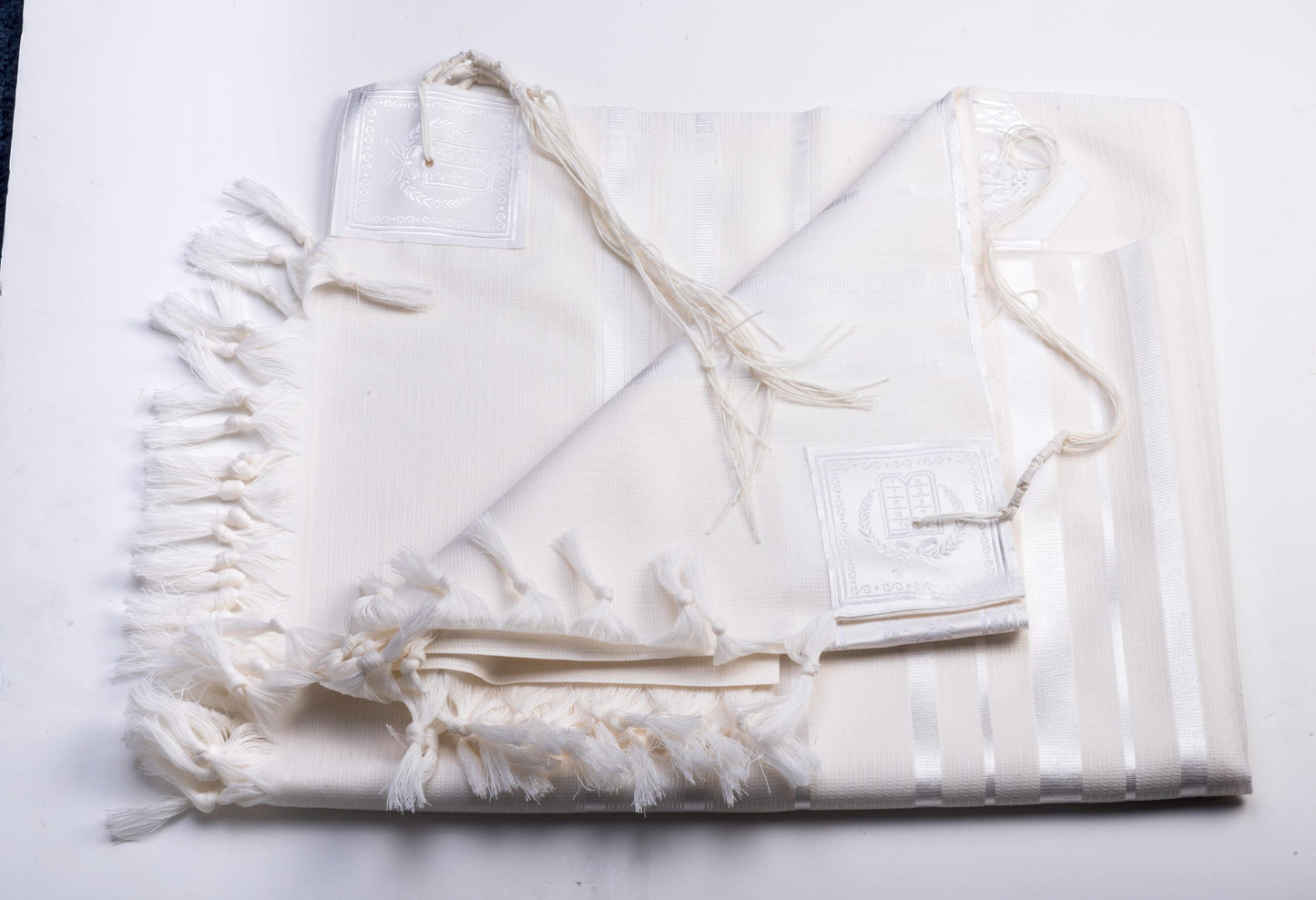 White wool tallit katan with tzitzit on a white background