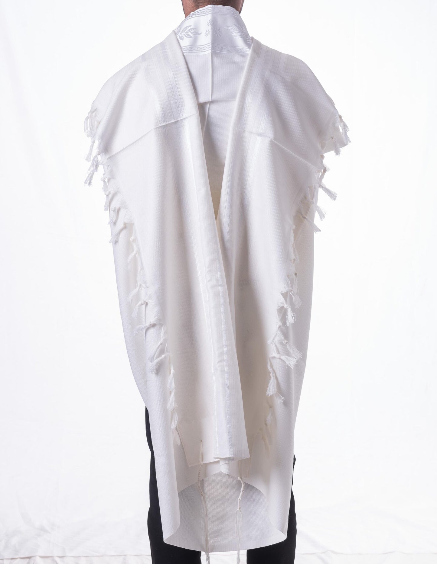 White shawl with fringe details draped over a person on a white background