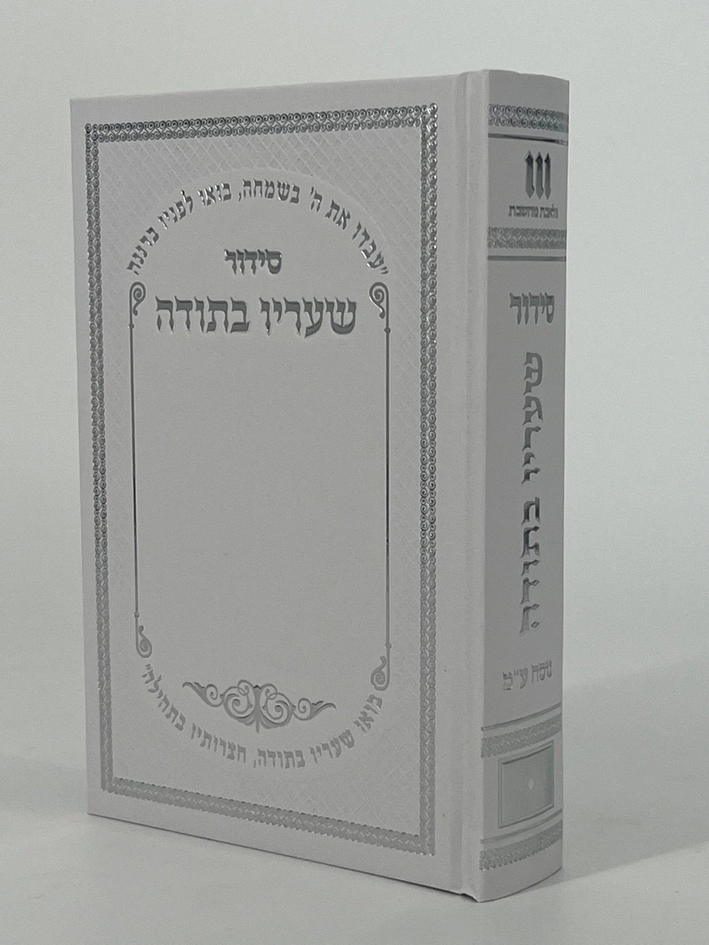 White hardcover Sha'arav B'Todah Siddur with silver-embossed Hebrew text and decorative border.