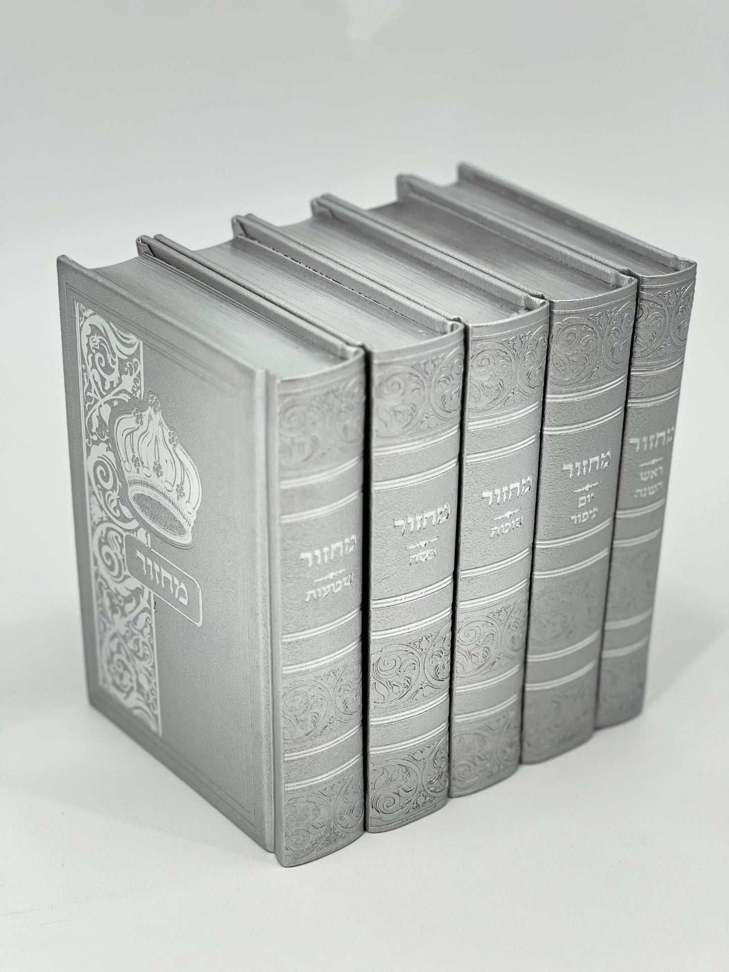 Five-volume Sha'arav B'Todah Sephardi Machzor set in silver-gray faux leather. Each volume features ornate embossed detailing, Hebrew titles, and a crown design on the front cover. The set includes Machzorim for Rosh Hashanah, Yom Kippur, Sukkot, Pesach, and Shavuot.