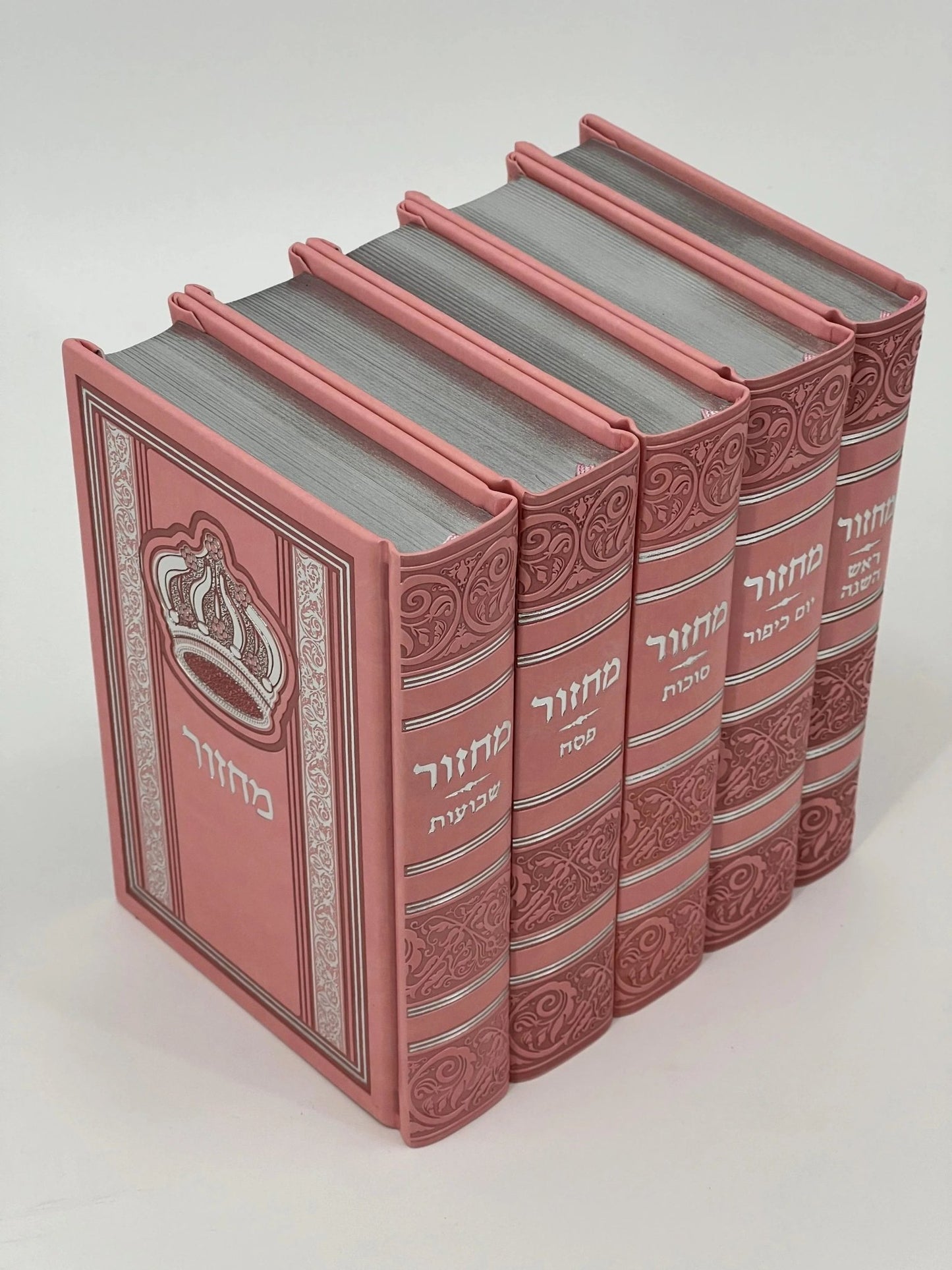 Five-volume Sha'arav B'Todah Sephardi Machzor set in pink faux leather covers with silver-embossed Hebrew titles. Each machzor features an ornate crown design and includes volumes for Rosh Hashanah, Yom Kippur, Sukkot, Pesach, and Shavuot.