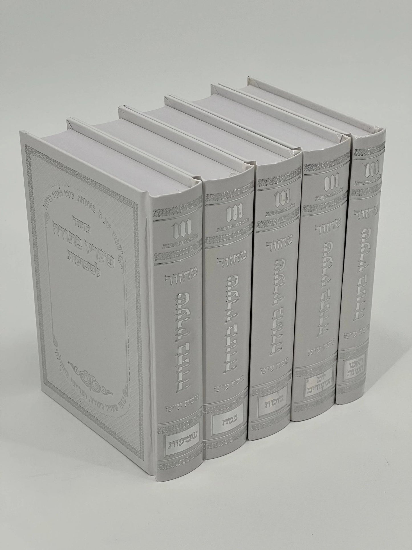 Five-volume Sha'arav B'Todah Sephardi Machzor set in white faux leather with white embossed Hebrew text and crown design. Each volume features ornate decorative spines and includes prayers for Rosh Hashanah, Yom Kippur, Sukkot, Pesach, and Shavuot.