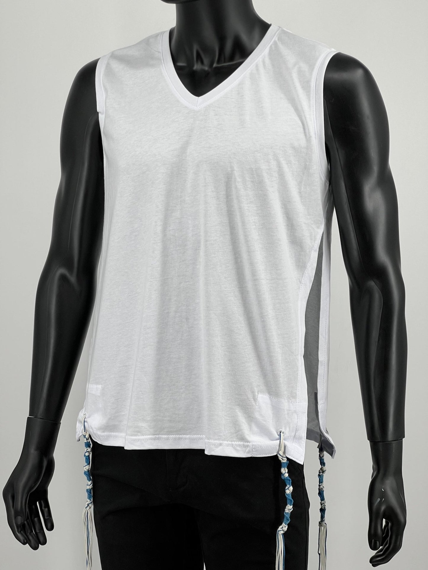 Front of white sleeveless Tzitzit undershirt on black mannequin with blue and white tzitzit strings at all four corners.