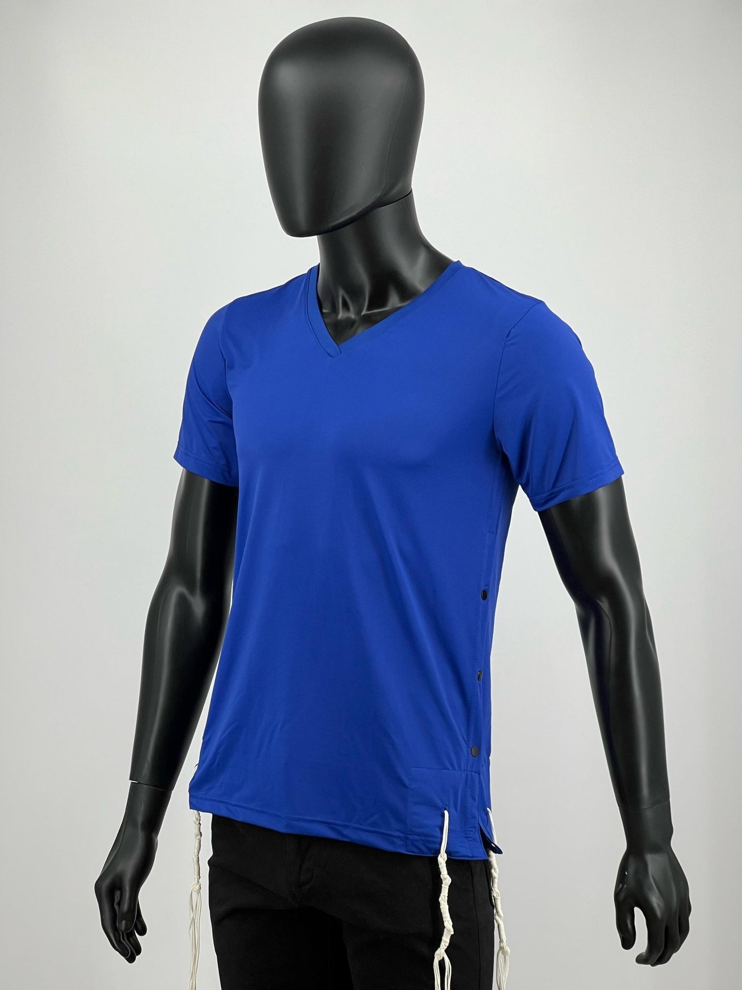 Front angled view of a blue athletic Tzitzit T-shirt with a V-neck design and side snap buttons, worn by a black mannequin. White Tzitzit strings hang from the hem, adhering to Jewish tradition.