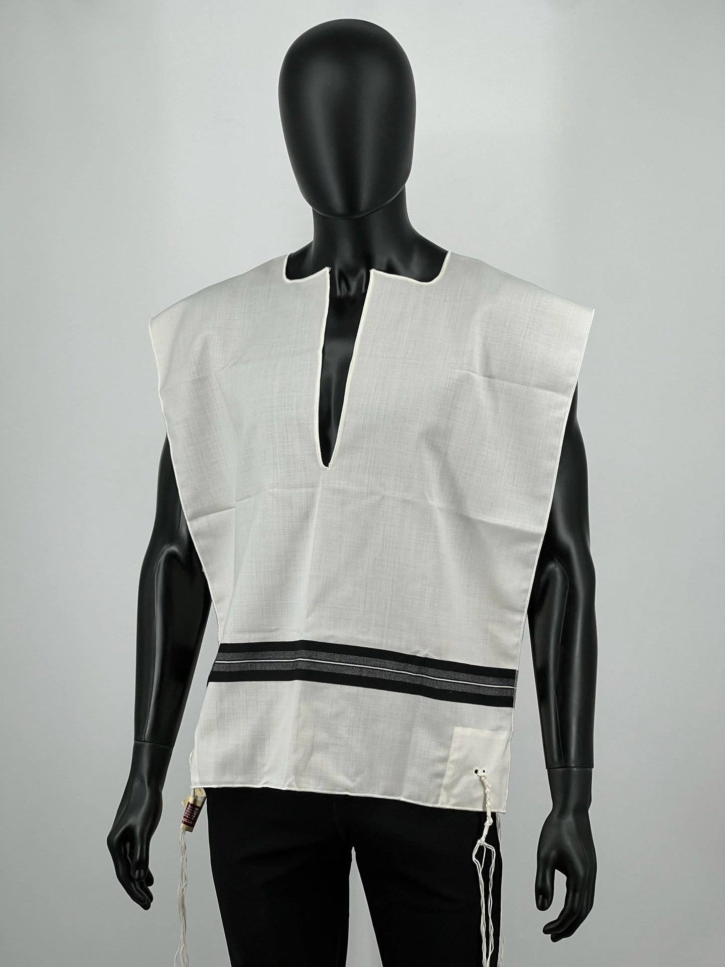Mannequin wearing a Ashkenazi tallit katan with a cutout design on a gray background