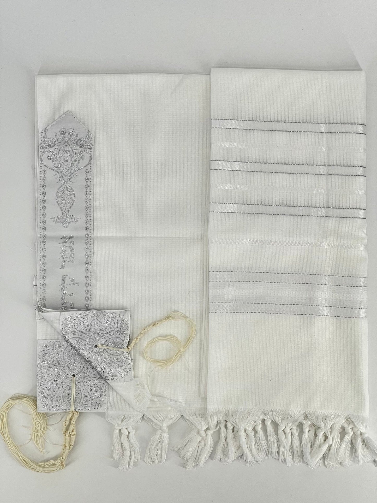 Flat-lay image of a white Acrylic Tallit Chatanim with silver stripes and silver decorative elements.