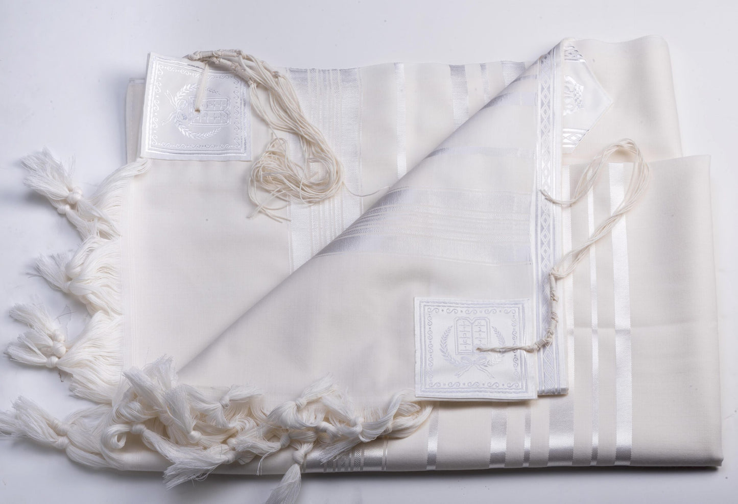 White prayer shawl with fringe on a light gray background