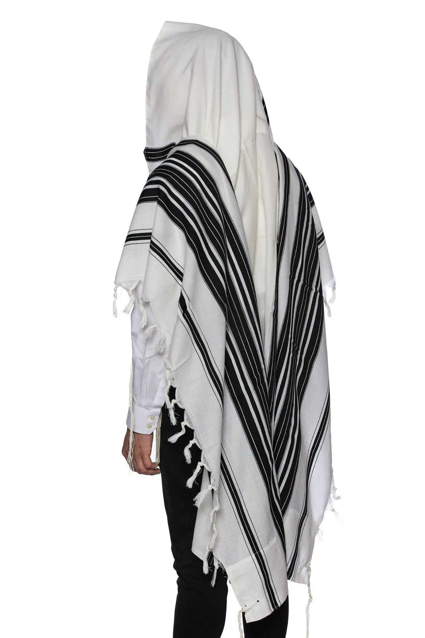A person wearing a black and silver striped tallit (prayer shawl) with white areas and fringes.