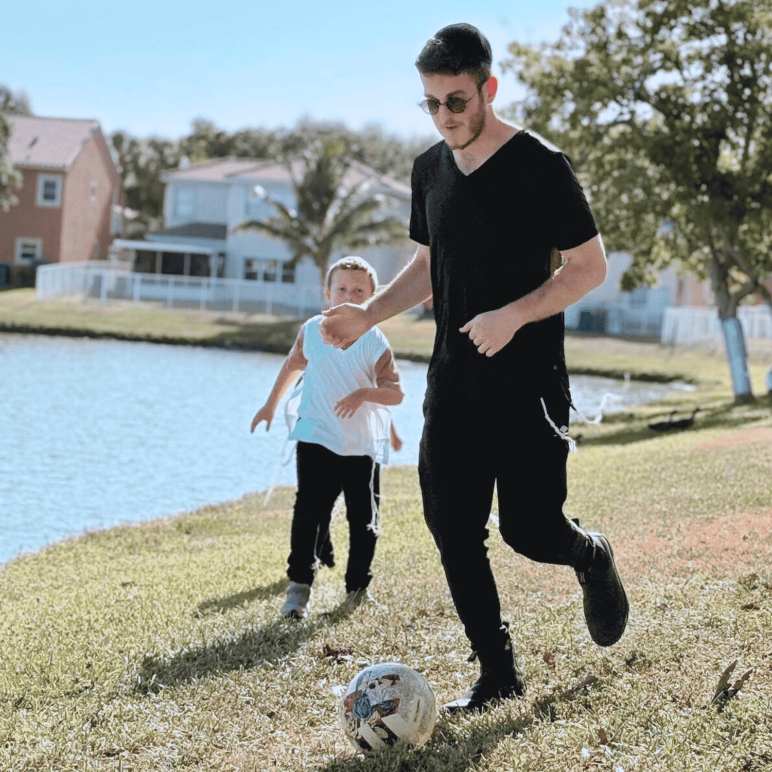 kids playing soccer outdoors, both wearing kosher tzitzit shirts from VeAhavta Judaica