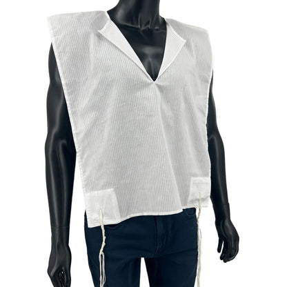 A white cotton Tallit Katan with vertical textured stripes, shown on a black mannequin torso. The garment features a V-shaped neckline and tzitzit strings hanging from the two front corners.