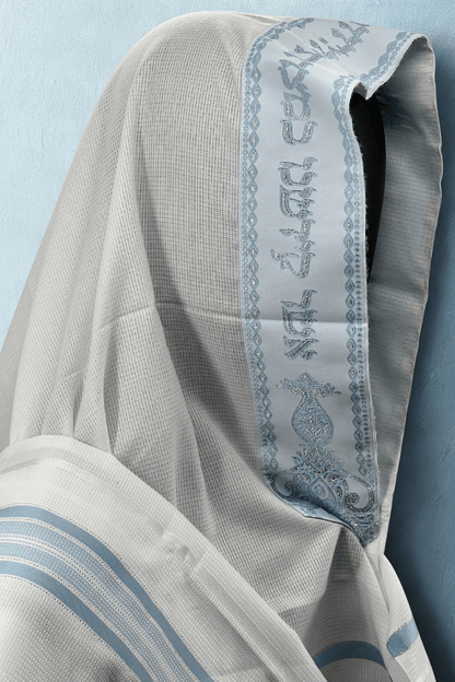 Close-up of a Tallit Chatanim with blue embroidery on a light blue background