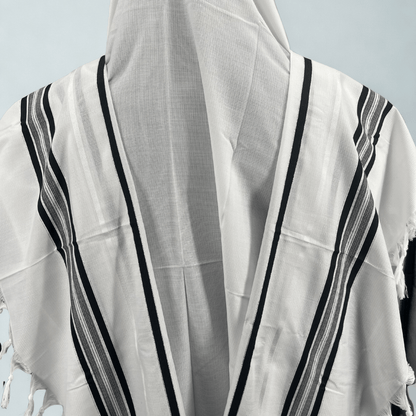 White Tallit Chatanim with black stripes draped over a mannequin against a light gray background