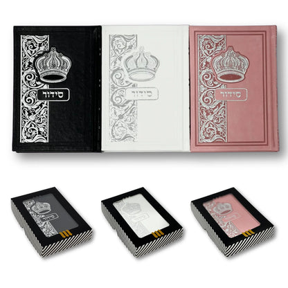A Siddur with faux leather binding, presented in black, white, and pink colors, featuring decorative floral and crown designs on the cover.
