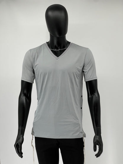 Mannequin dressed in a light gray V-neck short-sleeve Tzitzit T-shirt featuring black side buttons and white Tzitzit fringes hanging from the corners. The shirt is paired with black pants and displayed against a plain light background.