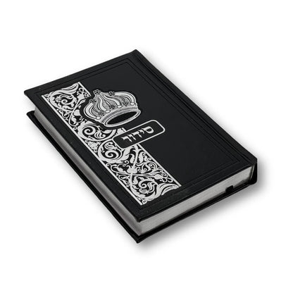 Black faux leather Siddur with an embossed crown and decorative floral design on the cover. The Hebrew word "סידור" appears in silver foil in the center. The book is slightly angled and closed, showing its elegant edges and craftsmanship.