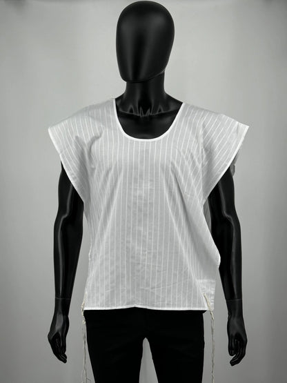 A white cotton Tallit Katan with vertical textured stripes, shown on a black mannequin torso. The garment features a V-shaped neckline and tzitzit strings hanging from the two front corners.
