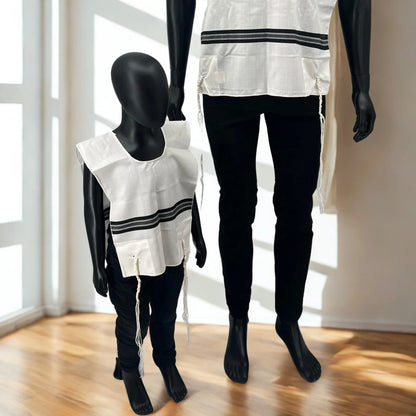 Two mannequins wearing white Chabad wool tallit katan with black  stripes and black pants in a room with large windows.