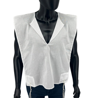 Close-up front view of a white cotton Tallit Katan worn on a black mannequin torso. The garment features a V-neck opening, fine vertical stripes, and visible kosher tzitzit strings hanging from the lower front corners.