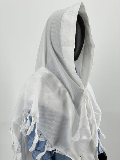 Child mannequin wearing a white Jewish prayer shawl with subtle woven patterns and white fringes (tzitzit) at the corners.