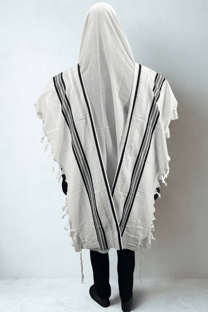 Person wearing a white prayer shawl with black stripes on a plain background