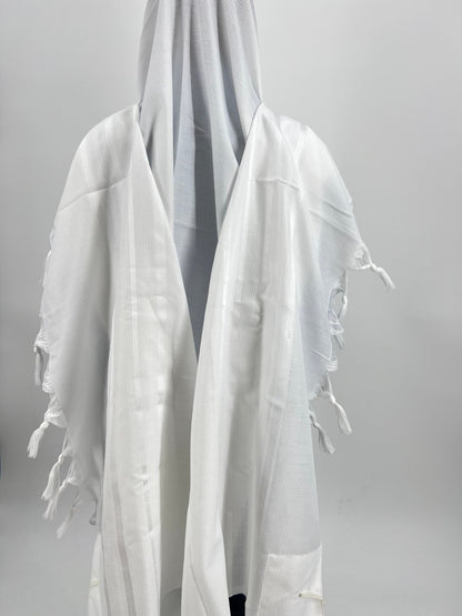Child wearing a plain white tallit (Jewish prayer shawl) with a hood, viewed from the back.