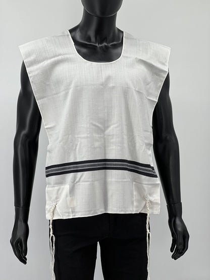 Front view of a mannequin wearing a white Tallit Katan with wide black striping across the chest and hand-tied Tzitzit strings hanging from the corners.