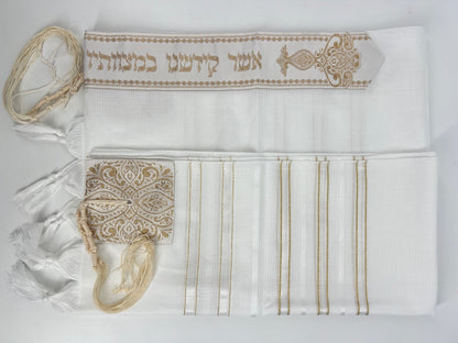 Folded white tallit prayer shawl with decorative gold embroidery, featuring tzitzit fringes and an ornate atarah