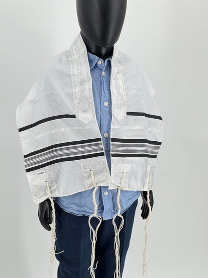 A children's tallit scarf displayed on a mannequin. The scarf is primarily white with black stripes and decorative elements.