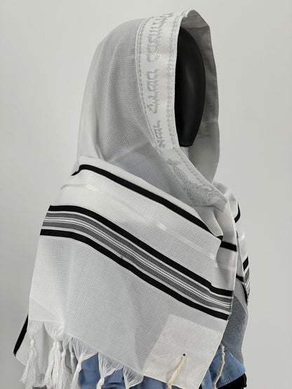 Child mannequin wearing a white tallit prayer shawl with black stripes and a silver atarah