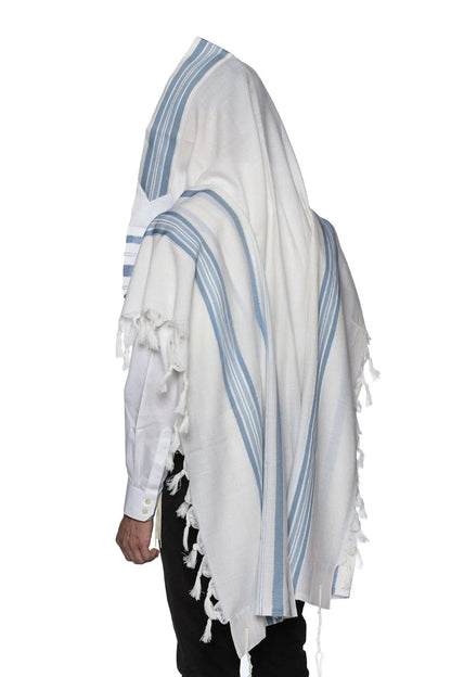 Man wearing a white wool Tallit with light blue stripes, draped over his head and shoulders in a traditional prayer posture.