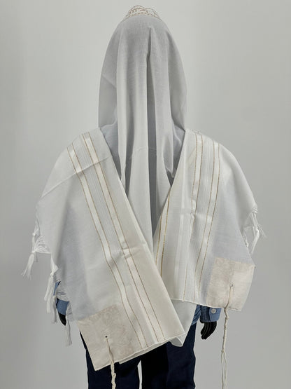 Child mannequin shown from the back wearing a white tallit prayer shawl with gold stripes and decorative corner patches