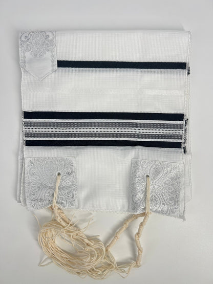 Folded white children's tallit (Jewish prayer shawl) featuring black and silver stripes,