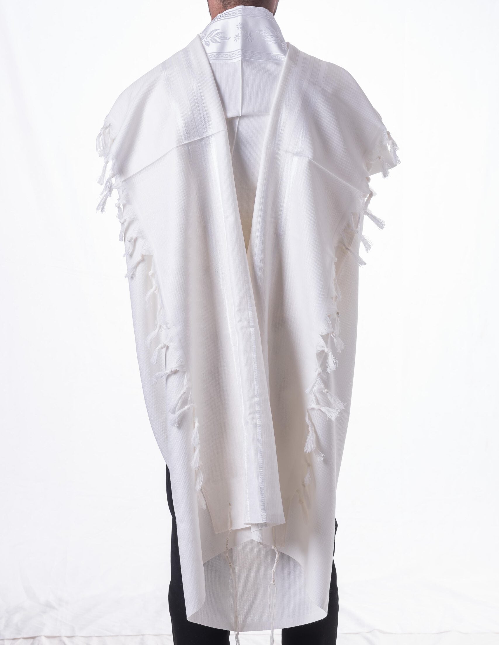 White shawl with fringe details draped over a person on a white background