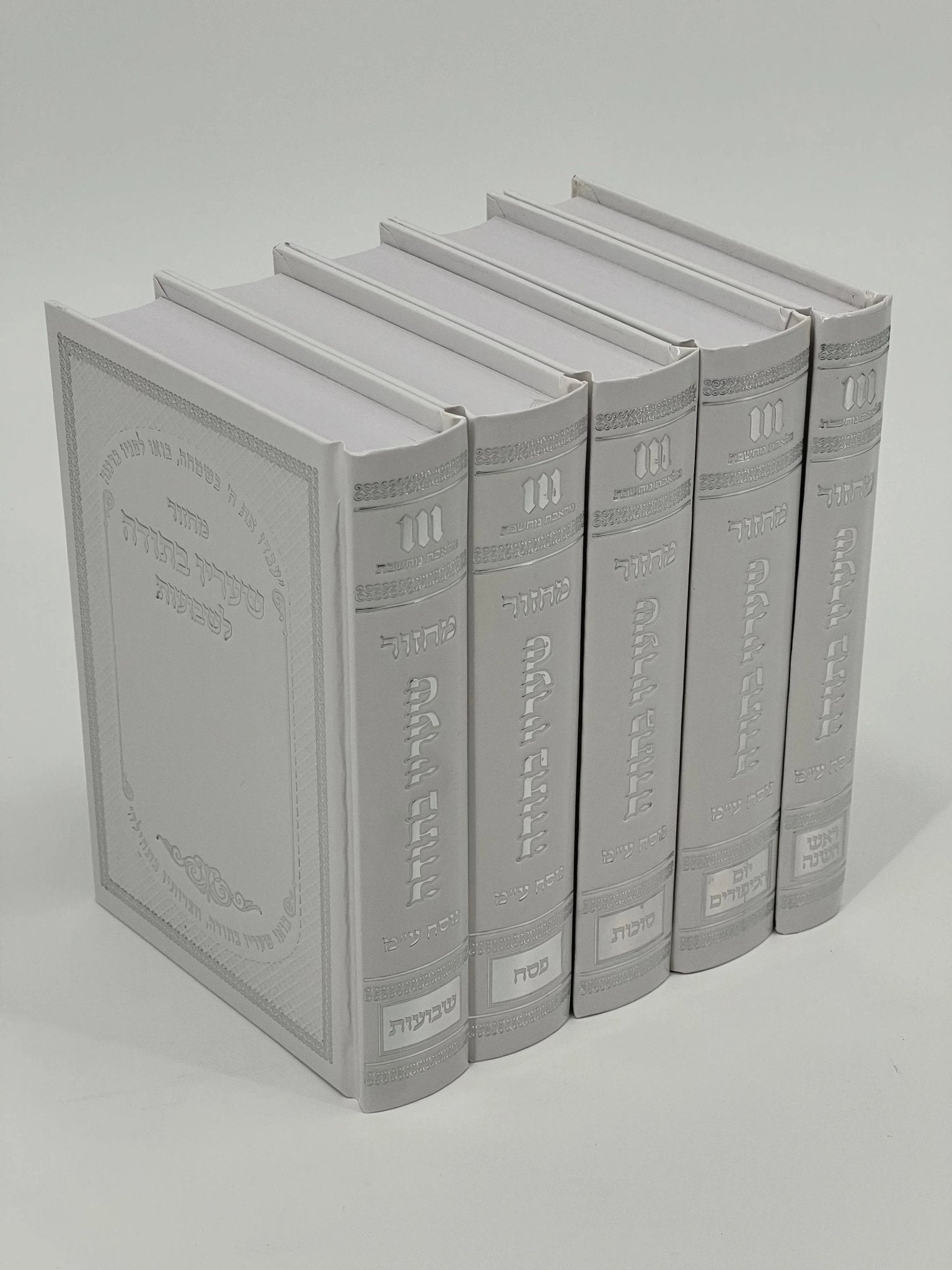 Five-volume Sha'arav B'Todah Sephardi Machzor set in glossy white faux leather with embossed silver Hebrew text and decorative details. Each volume includes prayers for a different Jewish holiday: Rosh Hashanah, Yom Kippur, Sukkot, Pesach, and Shavuot.