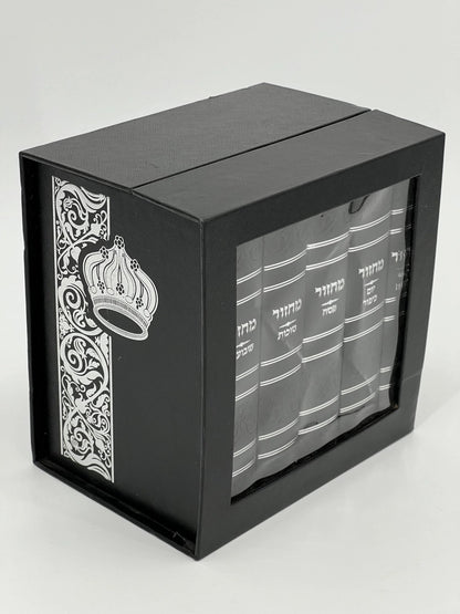 Five-volume Sha'arav B'Todah Sephardi Machzor set in a black faux leather case with a silver embossed crown and floral design. The front panel features a clear window displaying the white Hebrew titles of each machzor volume: Rosh Hashanah, Yom Kippur, Sukkot, Pesach, and Shavuot.
