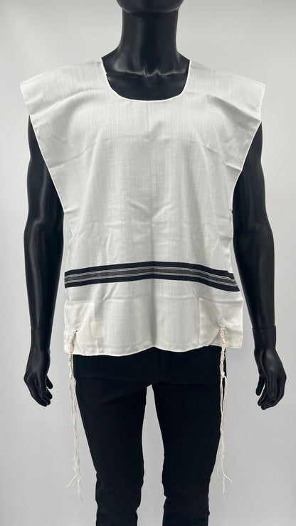 Front view of a mannequin wearing a white Tallit Katan with wide black striping across the chest and hand-tied Tzitzit strings hanging from the corners.